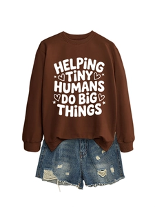 Close-up of brown sweatshirt with 'Helping Tiny Humans' text and ripped denim shorts