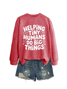 Flat lay of pink sweatshirt with 'Helping Tiny Humans' text and distressed denim shorts