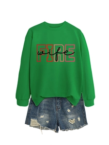 Close-up of green crewneck sweatshirt featuring red FIRE wife graphic print and denim shorts