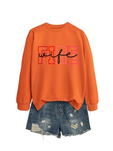 Flat lay of an orange crewneck sweatshirt with FIRE wife print and distressed denim shorts