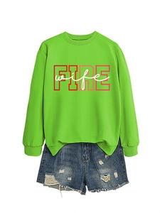 Detail of neon green crewneck sweatshirt with FIRE wife print and distressed denim shorts