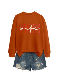 Detail of orange crewneck sweatshirt with FIRE wife print and distressed denim shorts