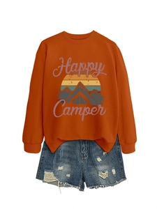 Détail du sweat orange Happy Camper avec motif rétro et short en jean bleu délavé à trous