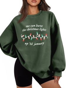 Detalle de una sudadera verde oscuro con estampado navideño y letras blancas de arte
