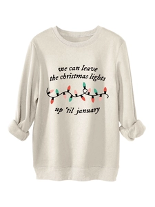 Detalle de la sudadera color albaricoque con estampado de luces navideñas y texto a mano