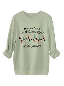 Primer plano de sudadera verde salvia con estampado de luces navideñas y texto artístico