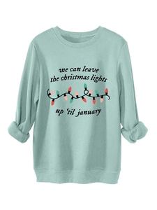 Detalle de sudadera verde menta con estampado navideño y diseño de luces de colores festivas