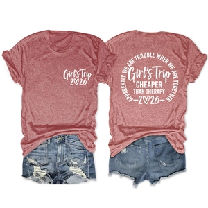 Detailed flat lay of brick red cotton T-shirt with Girl's Trip 2026 print and denim shorts