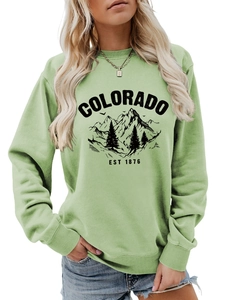 Close-up of the Colorado EST 1876 nature graphic printed on a green crewneck sweatshirt
