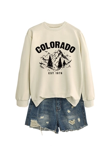 Flat lay of beige Colorado graphic sweatshirt paired with distressed denim shorts