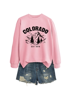 Detail of pink sweatshirt with mountain print and distressed blue denim shorts