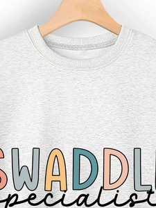Close-up of Swaddle specialist typography on a grey cotton crewneck sweatshirt