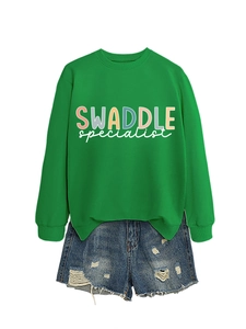 Flat lay of green round neck sweatshirt with SWADDLE print and ripped denim shorts