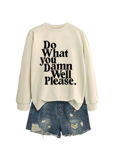 Flat lay of off-white crewneck sweatshirt with slogan and ripped denim shorts