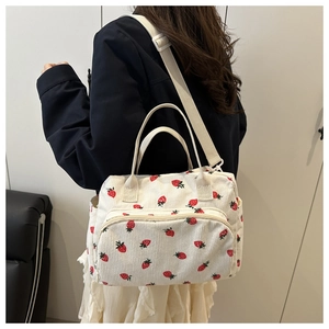 Corduroy tote bag with strawberry prints worn by a model to show size and style