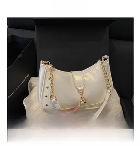 Close-up of white crescent bag with gold chain and buckle in premium gift box packaging