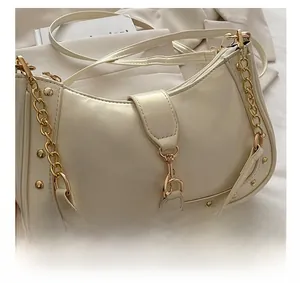 Close-up of cream leather crescent bag with gold stud rivets and polished chain detail