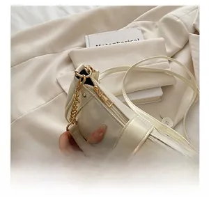 Close-up of white glossy shoulder bag showing smooth gold zipper and chain details