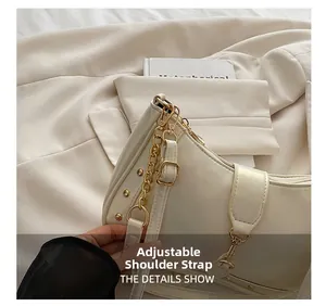 Detail of adjustable strap with gold chain and rivets on cream crescent bag