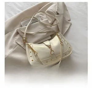 Detail of cream crescent bag with gold studs, metal clasp and leather strap contrast