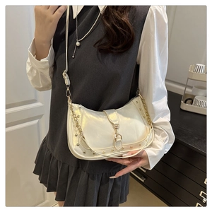 Detail of white pearl crescent bag featuring gold stud trim and metal buckle closure