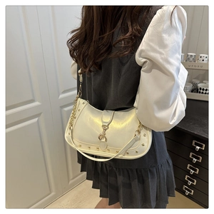 Detail of cream crescent bag featuring gold stud trim and metal chain shoulder strap