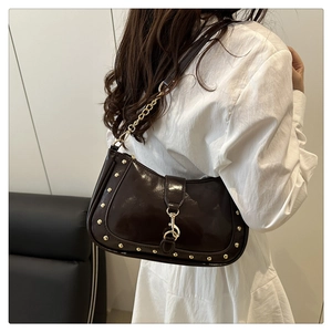 Close-up of chocolate brown patent leather shoulder bag with gold rivets and chain strap