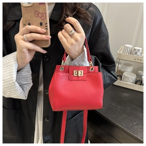 Detail of red lychee textured leather mini bag with gold twist lock and adjustable strap