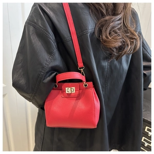 Détail du sac seau en cuir rouge texturé avec fermoir doré et poignée élégante