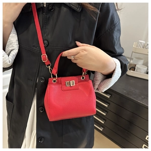 Detail of red pebbled leather mini bag featuring gold twist lock and shoulder strap