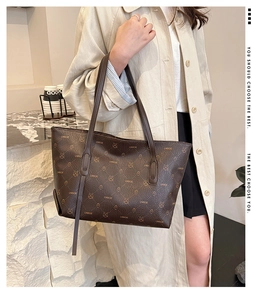 Detail of brown tote bag featuring bear monogram pattern and pebbled leather texture