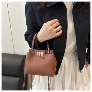 Brown litchi grain leather bag with gold twist lock worn by a model in casual style