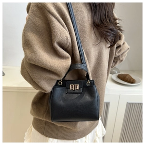 Détail du sac seau en cuir grainé noir avec fermoir tournant en métal et poignée