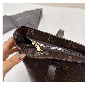 Detailed close-up of smooth gold metal zipper on brown textured leather tote bag