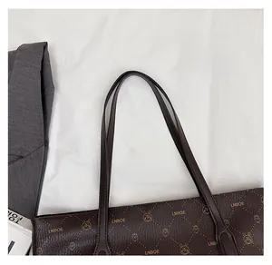 Detail view of the durable slim leather straps and gold branding on the brown tote bag