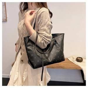 Close-up of black leather tote bag featuring litchi texture and printed cartoon bear patterns