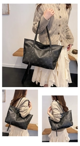 Close-up of black leather tote bag with letter prints and long shoulder straps