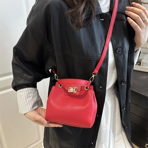 Sac seau rouge chic en cuir grainé avec fermoir doré porté par un mannequin élégant