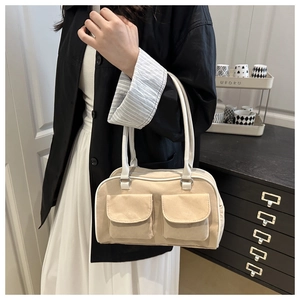 Close-up of beige canvas handbag showing flap pockets and white leather handle detail