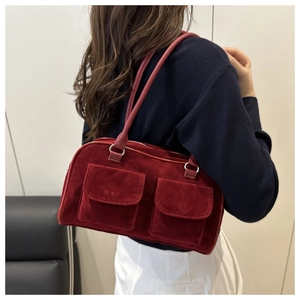 Detail of burgundy suede shoulder bag showing textured matte finish and front pockets