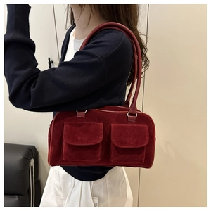 Detail view of red suede shoulder bag featuring retro double pocket design and silver rings