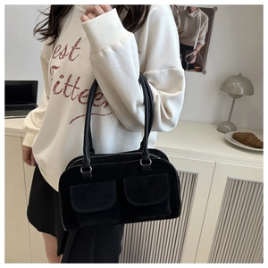 Close-up of black suede shoulder bag featuring dual front pockets and silver ring details