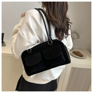 Lifestyle shot of black suede shoulder bag with dual front pockets and round strap
