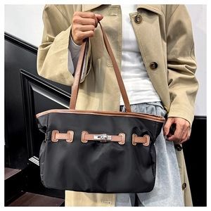 Detail einer schwarzen Nylon-Tasche mit braunen Lederriemen und Metallverschluss