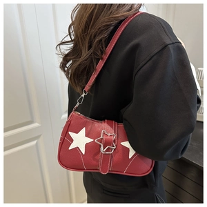 Detail view of red lychee leather underarm bag with white stars and silver star buckle