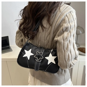 Detailed close-up of black leather underarm bag with white stars and metal buckle