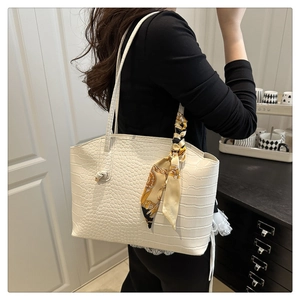 Detailed view of white crocodile pattern tote bag with silk scarf on the shoulder strap
