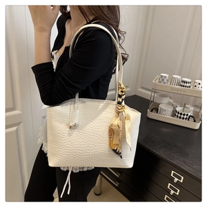 Close-up of white crocodile pattern tote bag with decorative silk scarf and metallic hardware