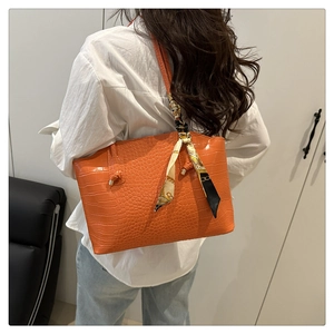 Dettaglio della borsa tote arancione coccodrillo con sciarpa decorativa in seta stampata