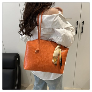 Detail of orange crocodile texture tote bag featuring a decorative printed silk scarf